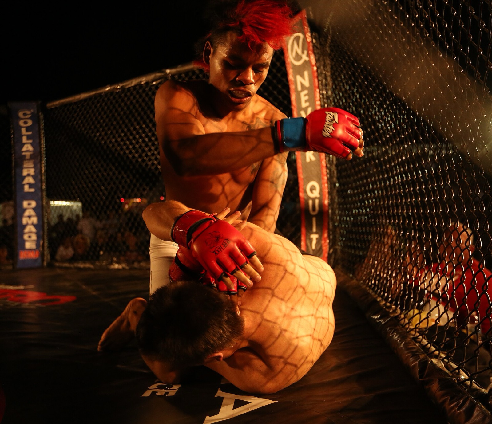 Fighters grappling against the cage